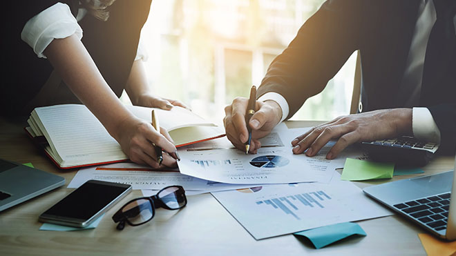 Two people reviewing pie charts