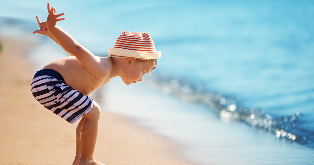 Child crouching at the shoreline of the beach
