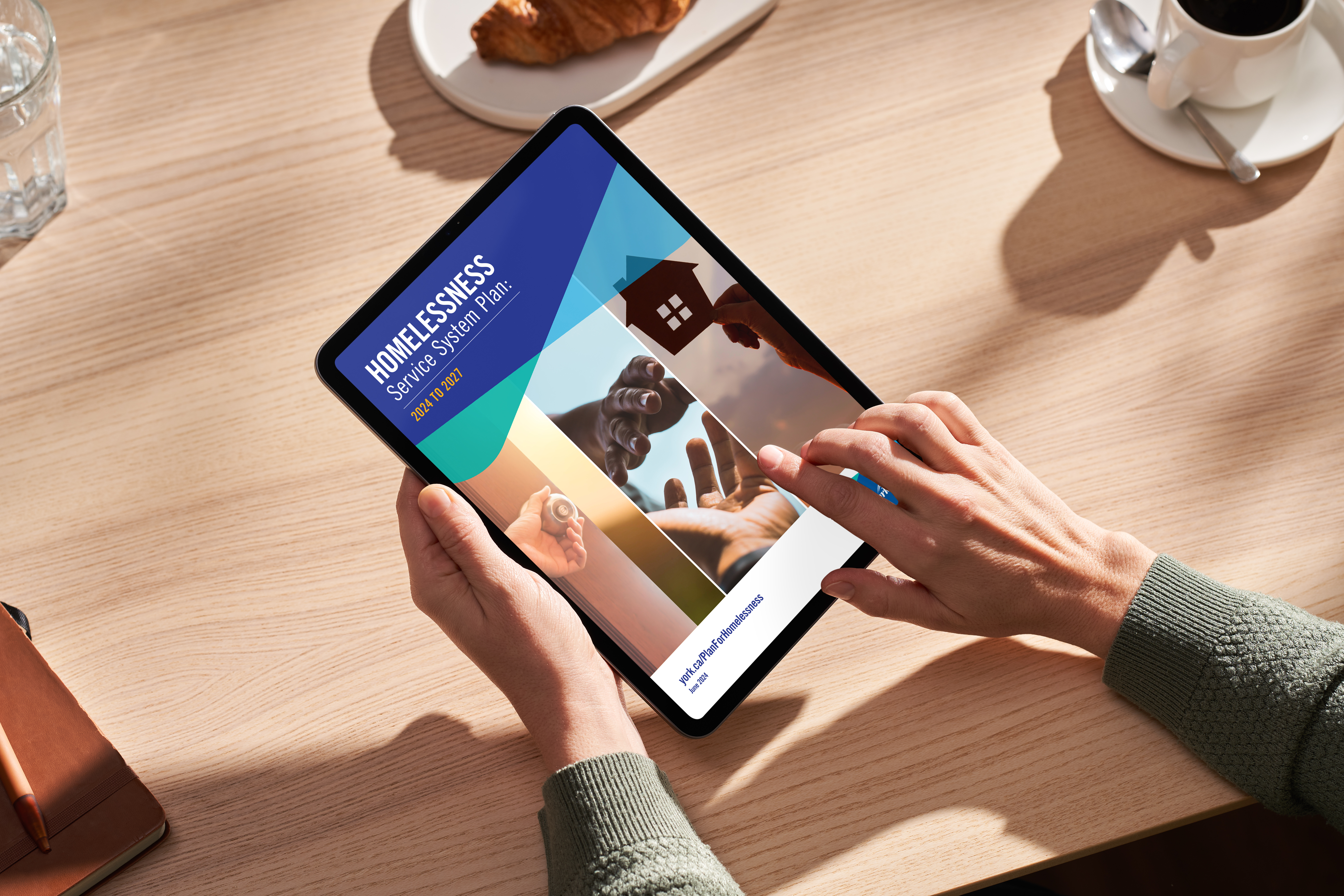 A person holding a tablet with an image of the Homelessness Plan cover