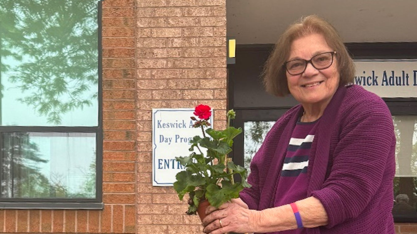 Woman smiling at the camera holding a plant