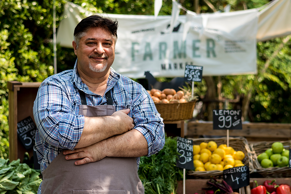 a vendor standing next to their vegetable stand