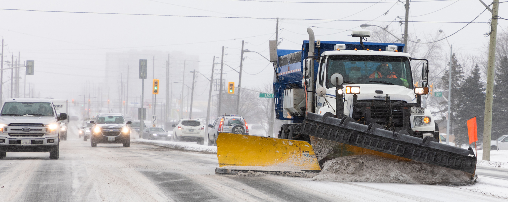 snow plow clearing snow and cars driving on the nearby