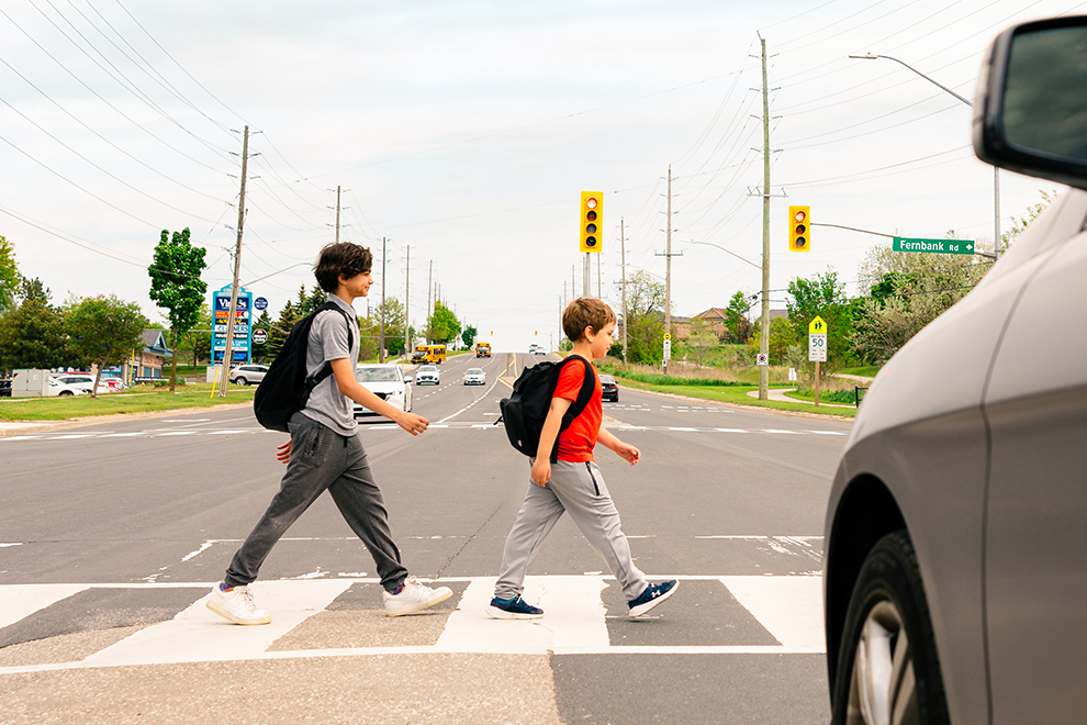 two children crossing at crosswalk with car stopped