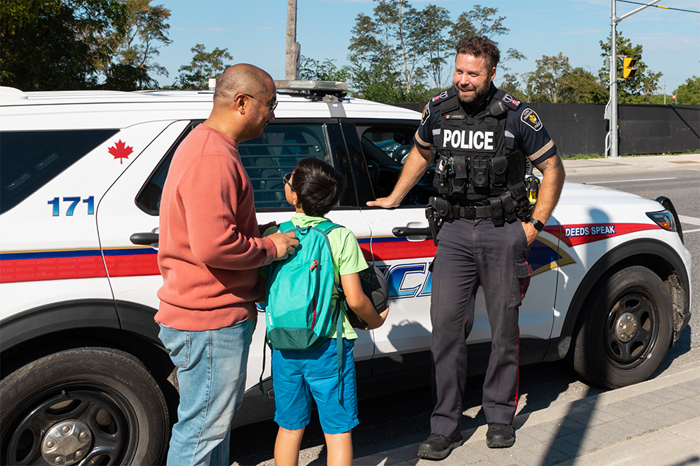 adult and child having a conversation with a police officer on the street