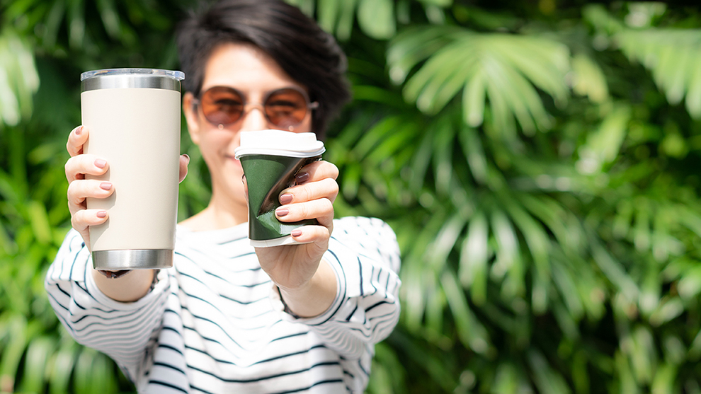 A women holding a reusable cup in one hand and squishing a disposable cup in her other hand