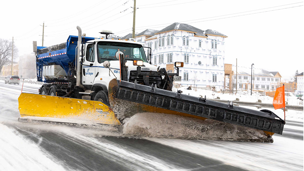 snow plow driving along a road with snow