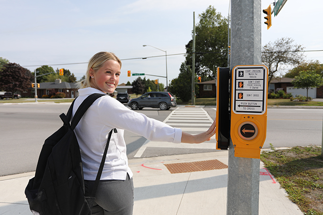 A girl pressing the traffic signal