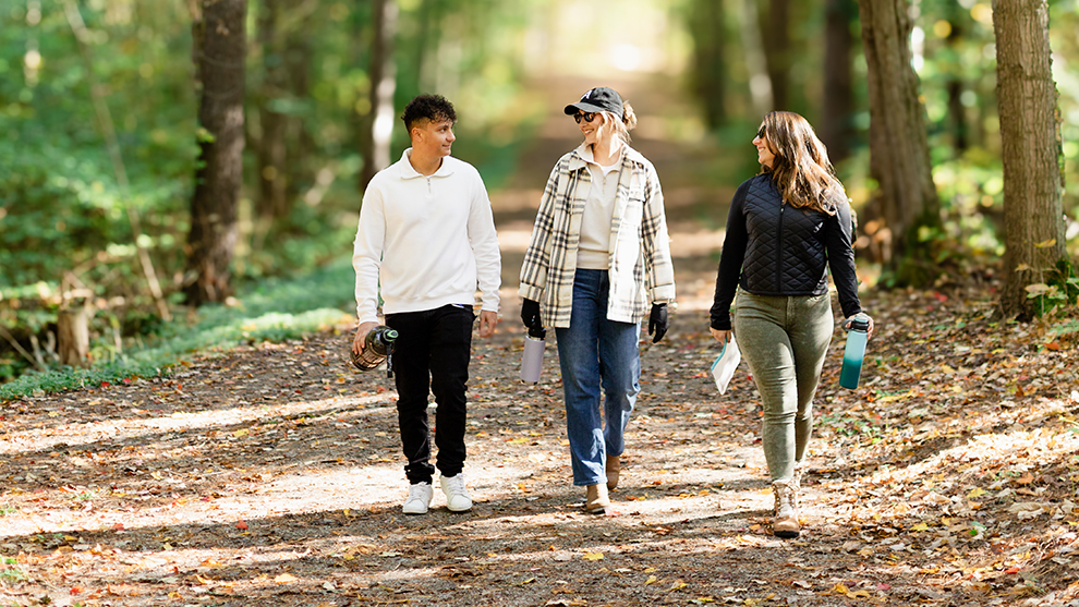 Three people walking on a forest trail