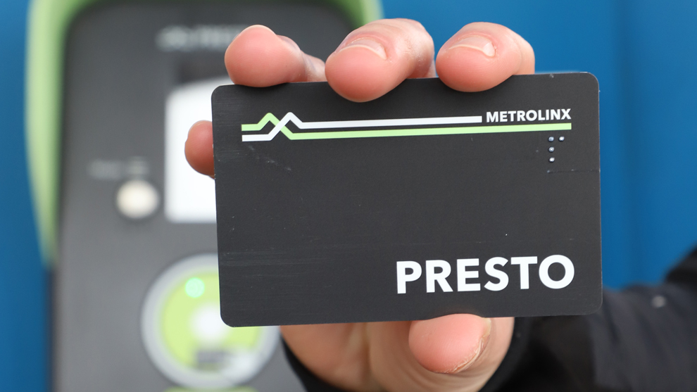 a person holding a PRESTO card in front of a PRESTO machine