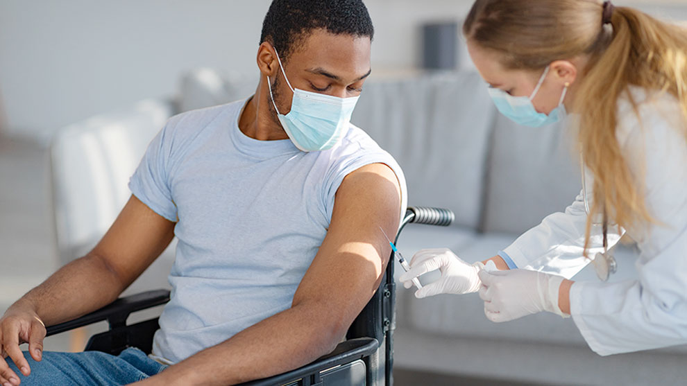 medical professional assisting a man in a wheelchair