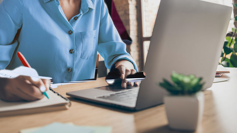 close up of person using laptop and taking notes