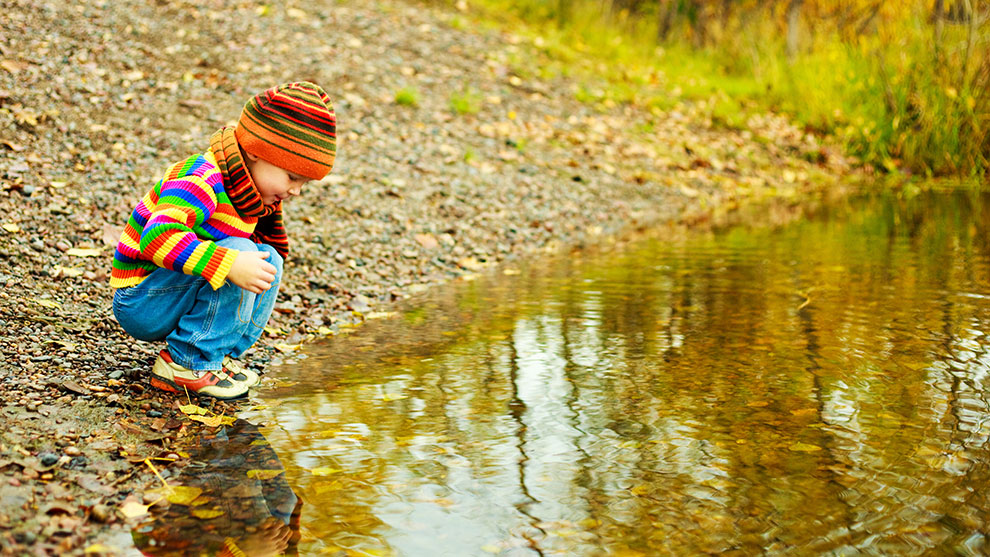 Little girl looking in water at her reflection