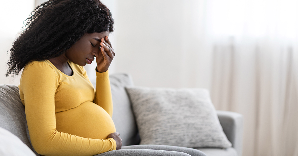 sad pregnant woman on couch