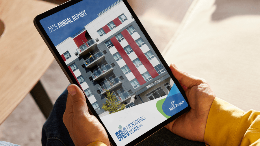 Hands holding a digital tablet with a "2025 HYI Annual Report" cover on the screen