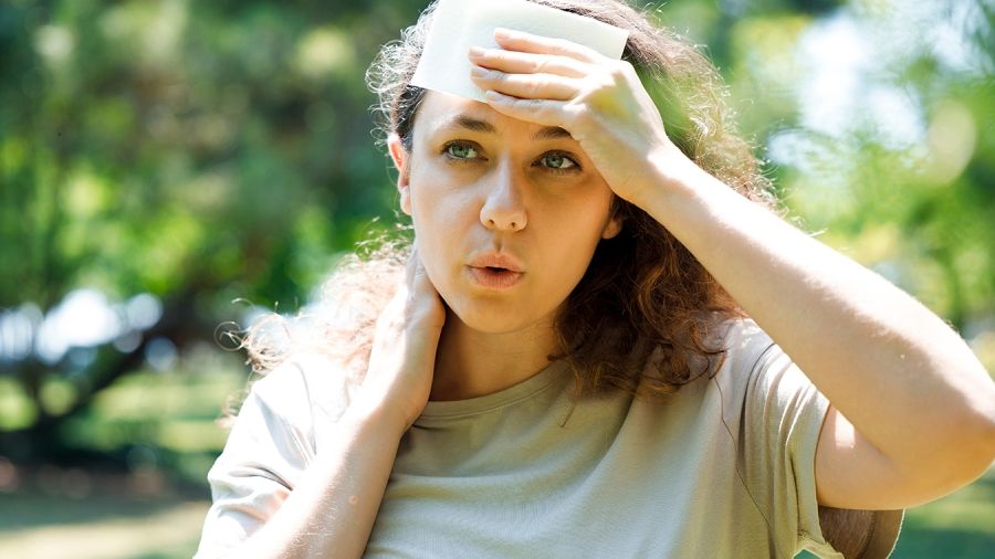 Person cooling their forehead outdoors on a hot day.