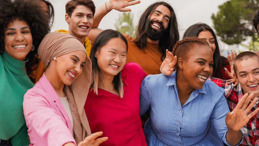 Group of people standing close together, some raising or waving their hands