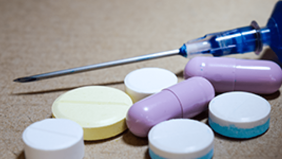 A syringe, several pill tablets and pill capsules