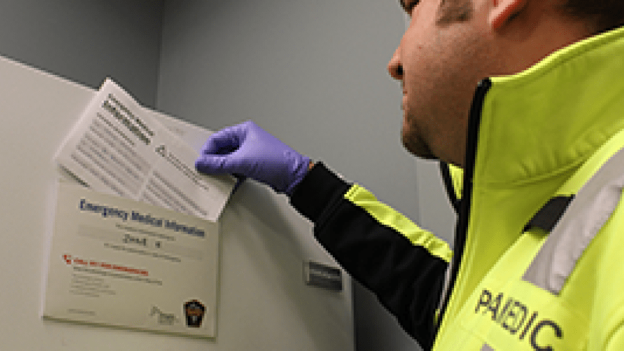 A paramedic is reviewing the emergency medical information sheet on a patient's refrigerator