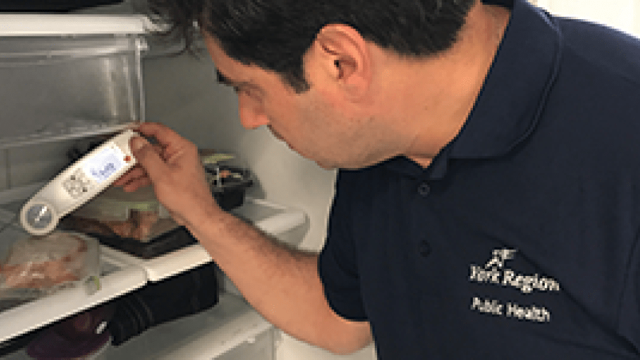A Public Health inspector conducting food storage safety tests in a refrigerator