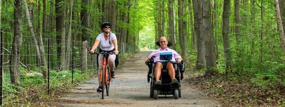 A cyclist and a person in a wheelchair enjoying an accessible trail in the York Regional Forest