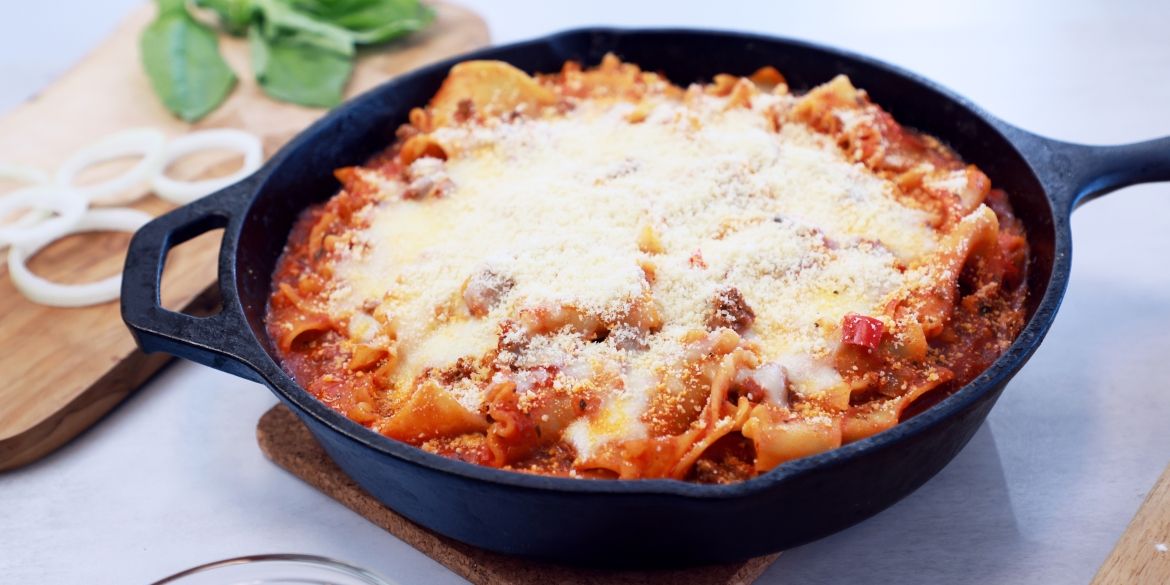 Skillet lasagna topped with melted cheese in a cast‑iron pan.