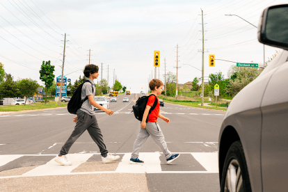 two children crossing at crosswalk with car stopped