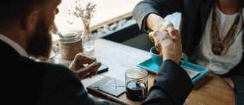 two people shaking hands over a table at a restaurant