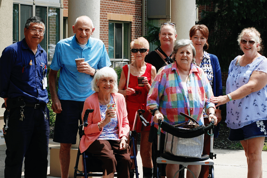 Group of seniors standing outside a building / Groupe de personnes âgées à l'extérieur d'un bâtiment