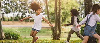 Children running around a tree, playing a game together