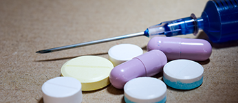 A syringe, several pill tablets and pill capsules