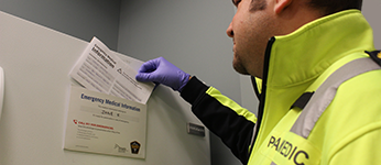 A paramedic is reviewing the emergency medical information sheet on a patient's refrigerator