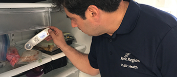 A Public Health inspector conducting food storage safety tests in a refrigerator